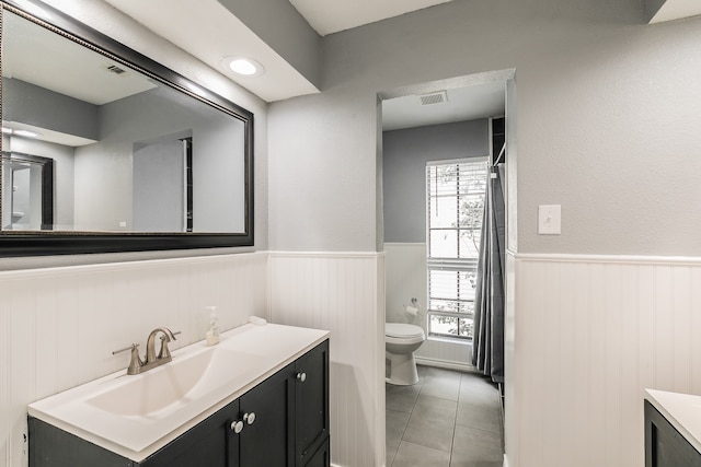 bathroom with toilet, vanity, and tile patterned flooring