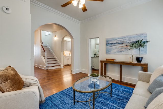 living room with ceiling fan, crown molding, and dark wood-type flooring