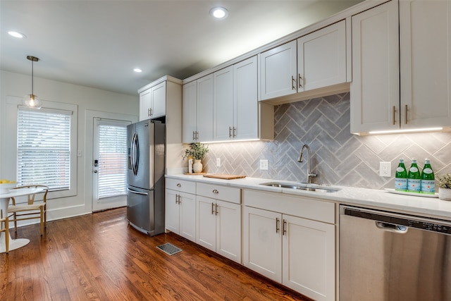 kitchen with dark wood-type flooring, sink, white cabinetry, appliances with stainless steel finishes, and decorative light fixtures