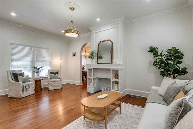 living room with hardwood / wood-style flooring, crown molding, and a tiled fireplace