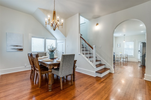 dining area with an inviting chandelier, wood-type flooring, and lofted ceiling