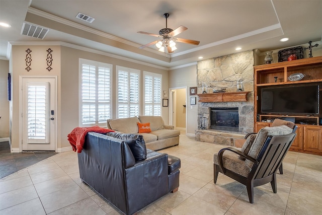 living room featuring crown molding, a stone fireplace, light tile patterned floors, and ceiling fan