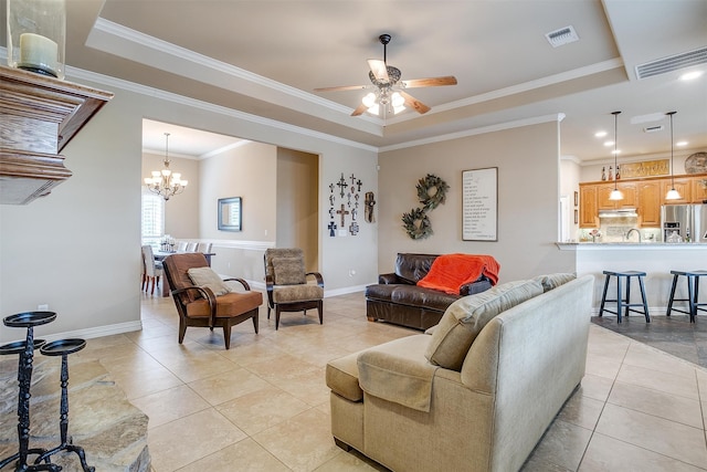 living room featuring light tile patterned floors, ceiling fan with notable chandelier, ornamental molding, and a tray ceiling