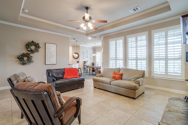 tiled living room with ceiling fan, a raised ceiling, and crown molding