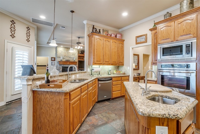 kitchen featuring pendant lighting, an island with sink, sink, kitchen peninsula, and stainless steel appliances