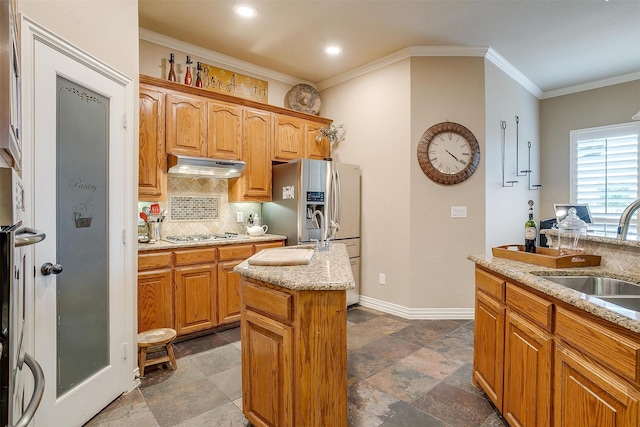 kitchen with appliances with stainless steel finishes, tasteful backsplash, a kitchen island, crown molding, and sink