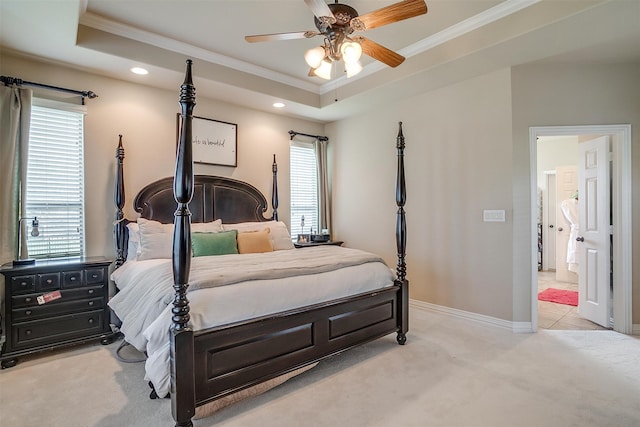 carpeted bedroom with a raised ceiling, connected bathroom, crown molding, and ceiling fan