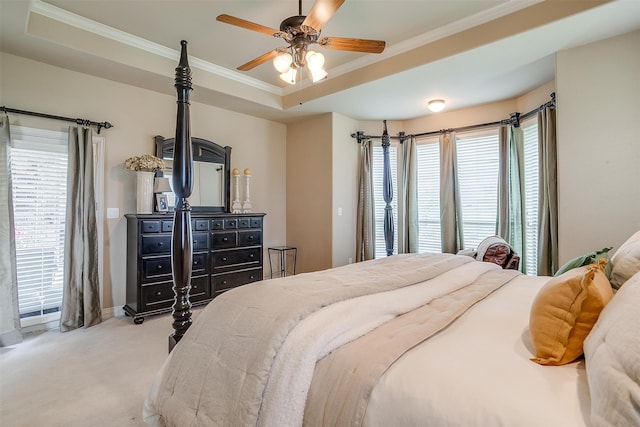 carpeted bedroom featuring multiple windows, a tray ceiling, and ceiling fan