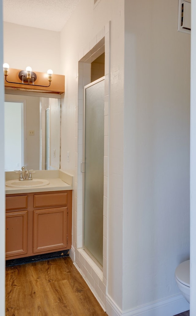 bathroom with vanity, hardwood / wood-style floors, a shower with shower door, toilet, and a textured ceiling