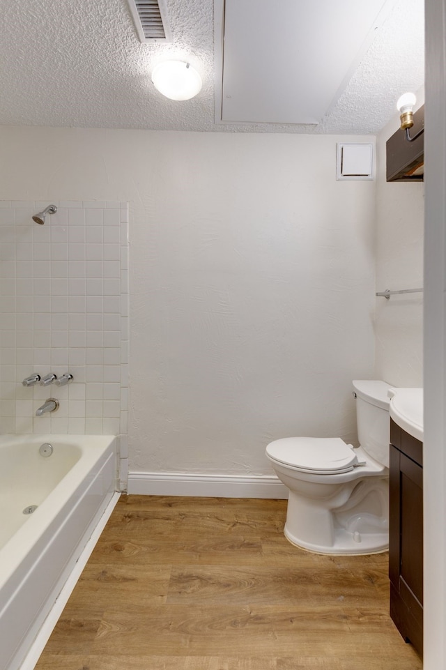 full bathroom with vanity, hardwood / wood-style flooring, bathtub / shower combination, toilet, and a textured ceiling