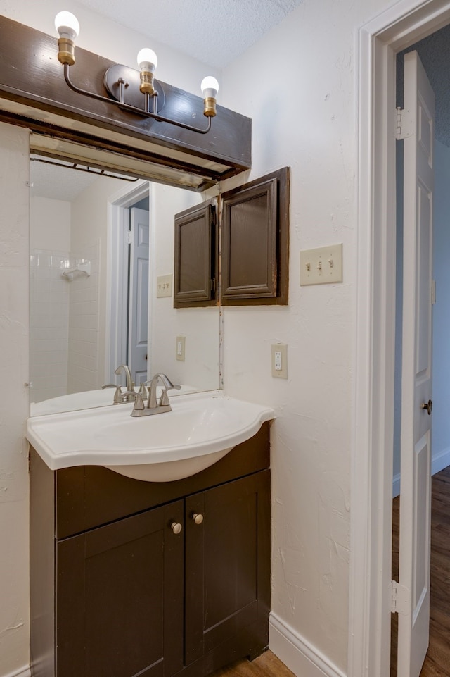 bathroom featuring hardwood / wood-style flooring, vanity, and a textured ceiling