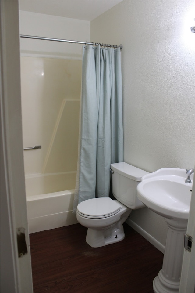 bathroom with hardwood / wood-style floors, toilet, and shower / tub combo with curtain