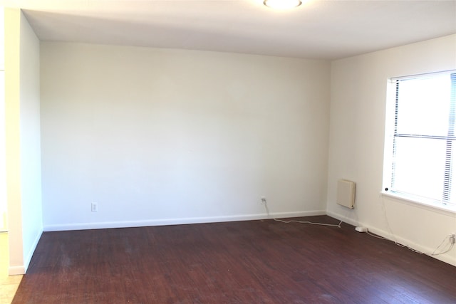 spare room featuring a healthy amount of sunlight and dark hardwood / wood-style flooring