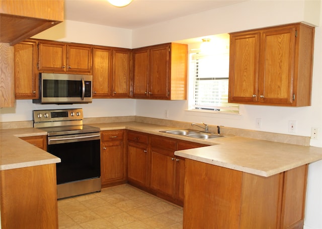 kitchen with appliances with stainless steel finishes, sink, and kitchen peninsula