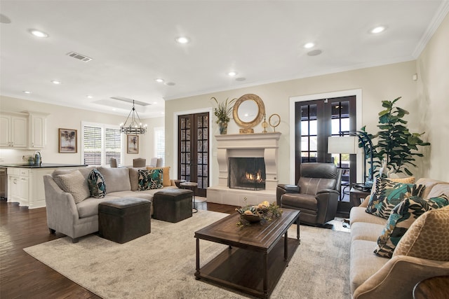 living room with wood-type flooring, sink, a notable chandelier, ornamental molding, and french doors