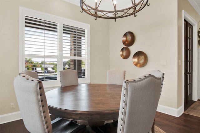 dining area with ornamental molding, an inviting chandelier, and dark wood-type flooring