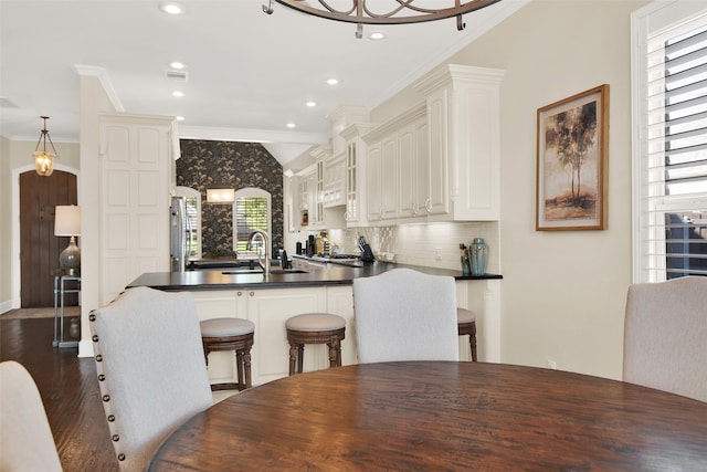 kitchen with ornamental molding, white cabinets, kitchen peninsula, and dark hardwood / wood-style floors