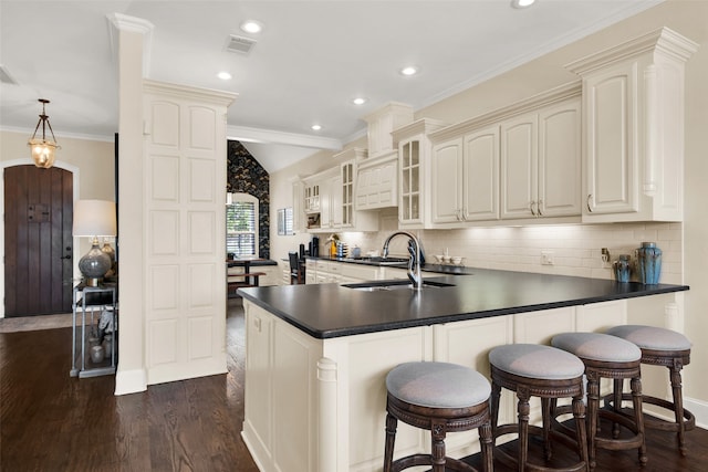 kitchen featuring pendant lighting, dark hardwood / wood-style flooring, sink, decorative backsplash, and crown molding