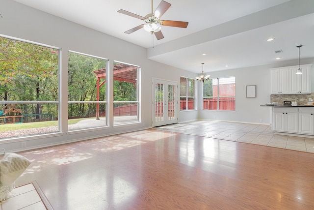 interior space featuring ceiling fan with notable chandelier, light hardwood / wood-style flooring, and plenty of natural light