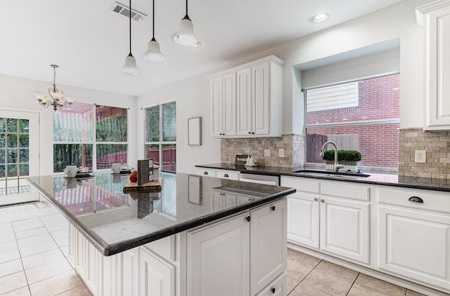 kitchen with backsplash, white cabinetry, a center island, and decorative light fixtures