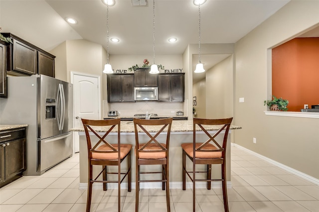 kitchen featuring dark brown cabinetry, a kitchen island with sink, a breakfast bar, and appliances with stainless steel finishes