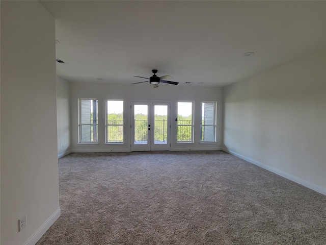 carpeted empty room with ceiling fan, a wealth of natural light, and french doors