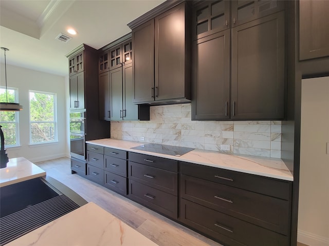 kitchen featuring black electric cooktop, pendant lighting, light hardwood / wood-style flooring, dark brown cabinets, and backsplash