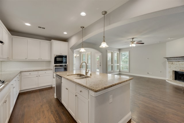 kitchen with ceiling fan, hanging light fixtures, sink, a stone fireplace, and stainless steel appliances