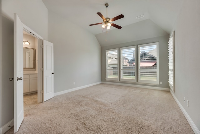 interior space featuring lofted ceiling, ceiling fan, light colored carpet, and ensuite bath