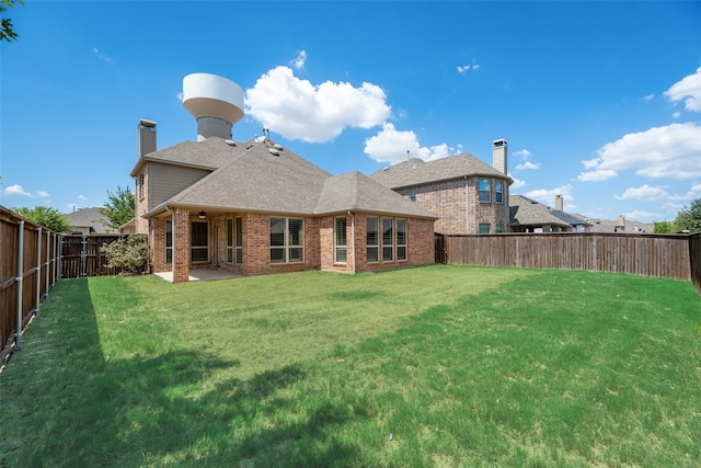 rear view of house featuring a lawn and a patio