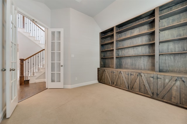 carpeted empty room with vaulted ceiling and french doors