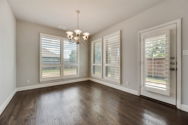 unfurnished dining area with a notable chandelier, a wealth of natural light, and dark wood-type flooring