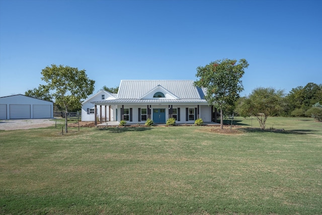 country-style home featuring covered porch, a garage, a front yard, and an outbuilding