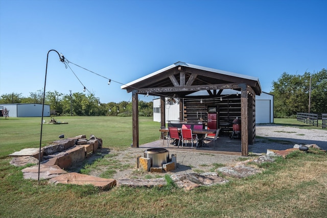 view of home's community with an outdoor structure, a lawn, and a patio area