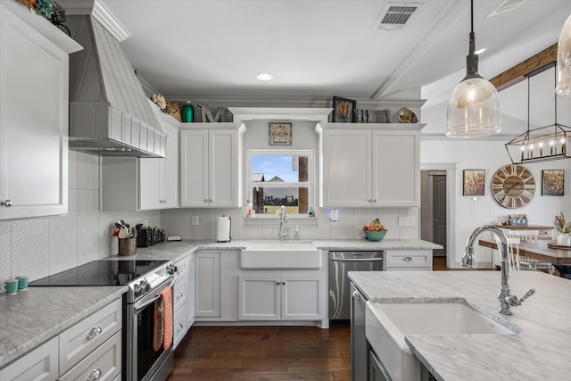 kitchen with white cabinets, custom range hood, appliances with stainless steel finishes, and sink