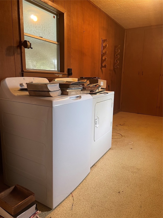 clothes washing area with light colored carpet, wood walls, and independent washer and dryer