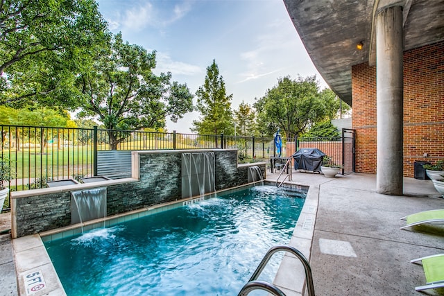 view of pool with area for grilling, pool water feature, and a patio area