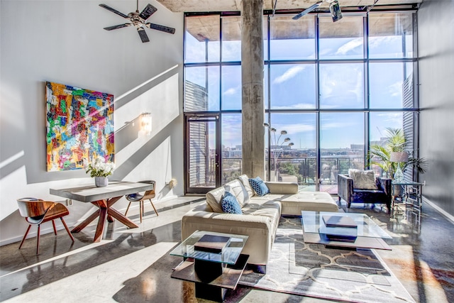 living room featuring floor to ceiling windows, concrete floors, a towering ceiling, and ceiling fan