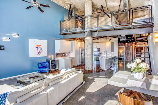 living room featuring ceiling fan, beverage cooler, sink, and a high ceiling