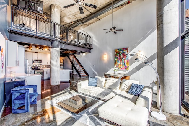 living room with ceiling fan, a towering ceiling, and concrete floors