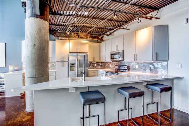 kitchen with appliances with stainless steel finishes, kitchen peninsula, and a breakfast bar