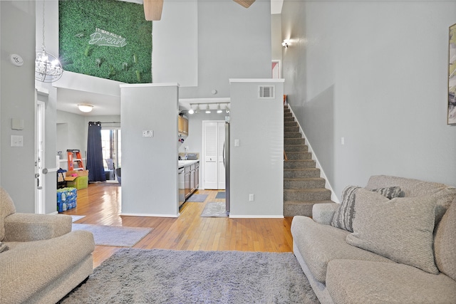 living room with a high ceiling, light hardwood / wood-style floors, and an inviting chandelier