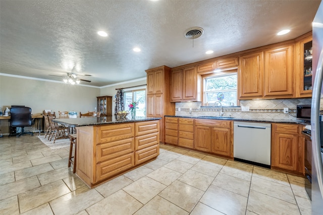 kitchen with a healthy amount of sunlight, dishwasher, ceiling fan, and sink