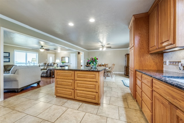 kitchen featuring ceiling fan, light tile patterned floors, backsplash, dark stone counters, and crown molding