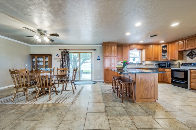 kitchen featuring sink, a kitchen bar, a kitchen island, black appliances, and ceiling fan