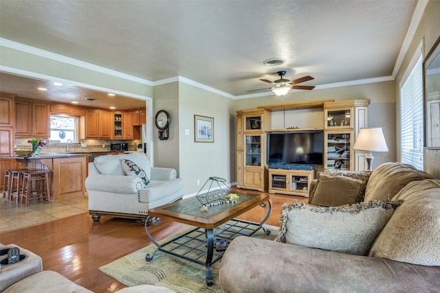 living room with ornamental molding, light wood-type flooring, and ceiling fan