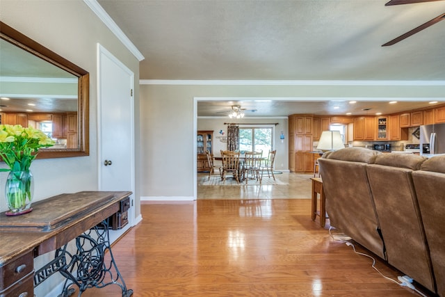 living room with crown molding, light hardwood / wood-style floors, and ceiling fan