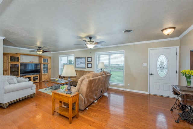 living room with ceiling fan, a textured ceiling, light wood-type flooring, and crown molding