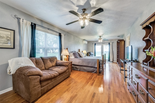 bedroom featuring ceiling fan, a textured ceiling, light wood-type flooring, and french doors