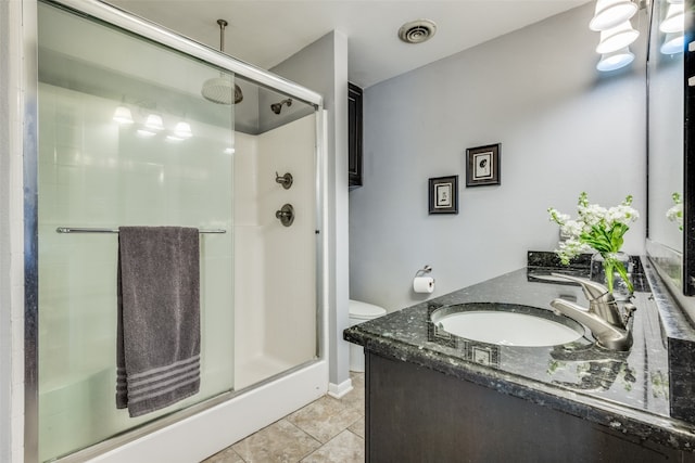 bathroom with tile patterned flooring, vanity, toilet, and a shower with door